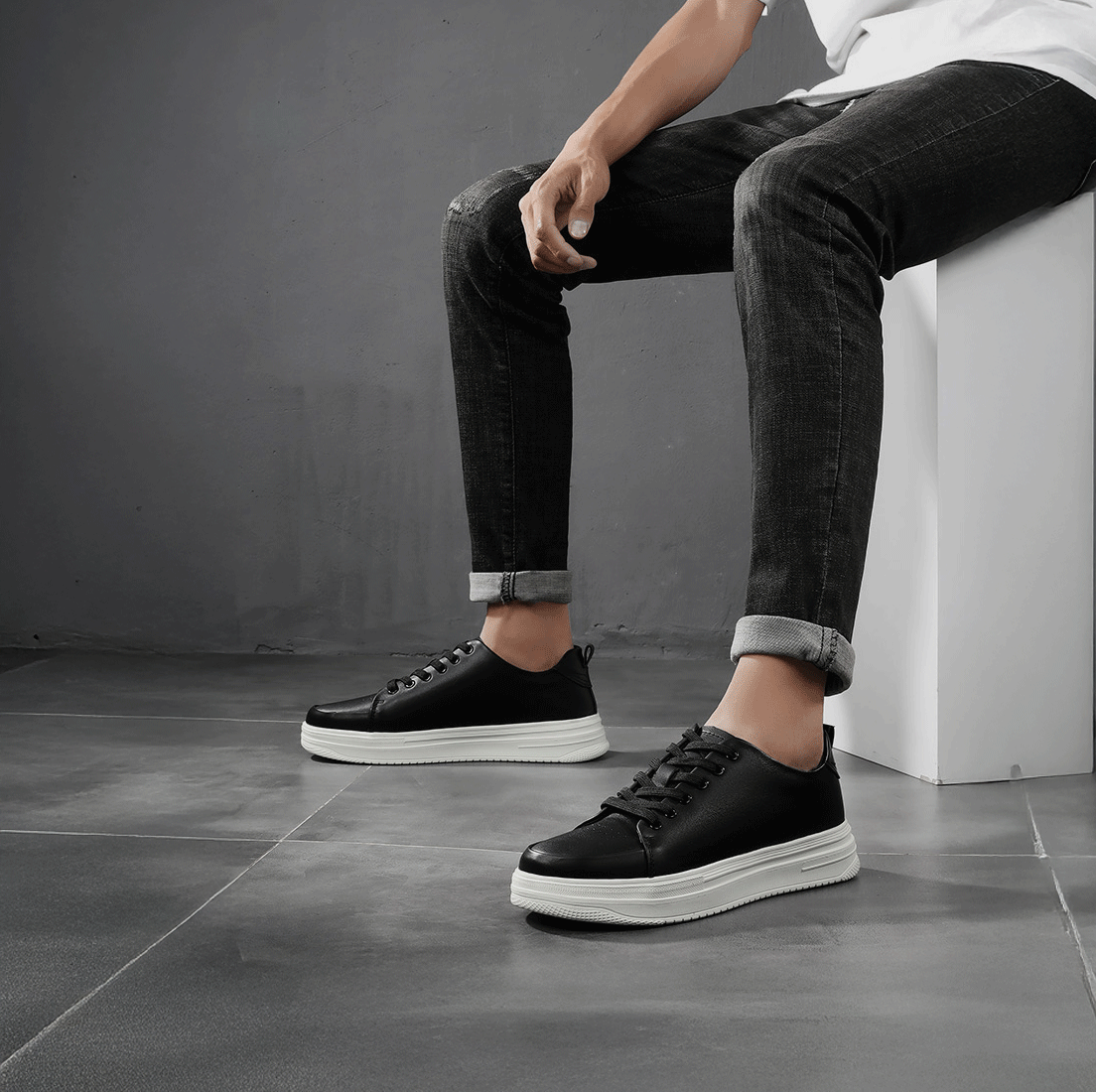 Man Sitting on a Block Wearing Black Cruze Sneakers | Levante Shoes