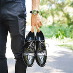 image of man holding elevator dress shoes
