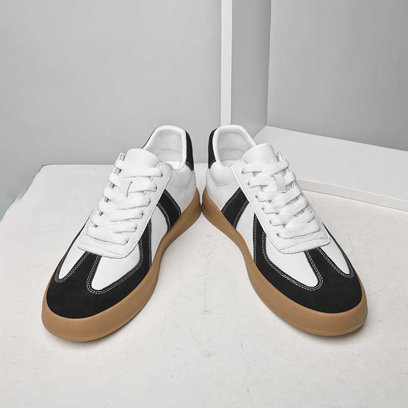 Pair of black and white sneakers with brown soles on a light gray background