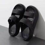 Black sandals resting on a wall on a light gray background