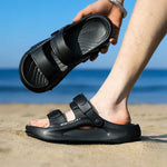 Person wearing black elevator sandals on a beach with ocean view