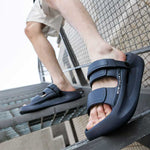 Person wearing grey height boosting sandals standing on metal stairs.