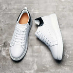 Pair of white sneakers with black accents on a gray concrete surface