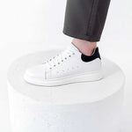White sneakers worn with gray pants on a white background