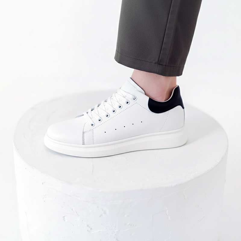 White sneakers worn with gray pants on a white background