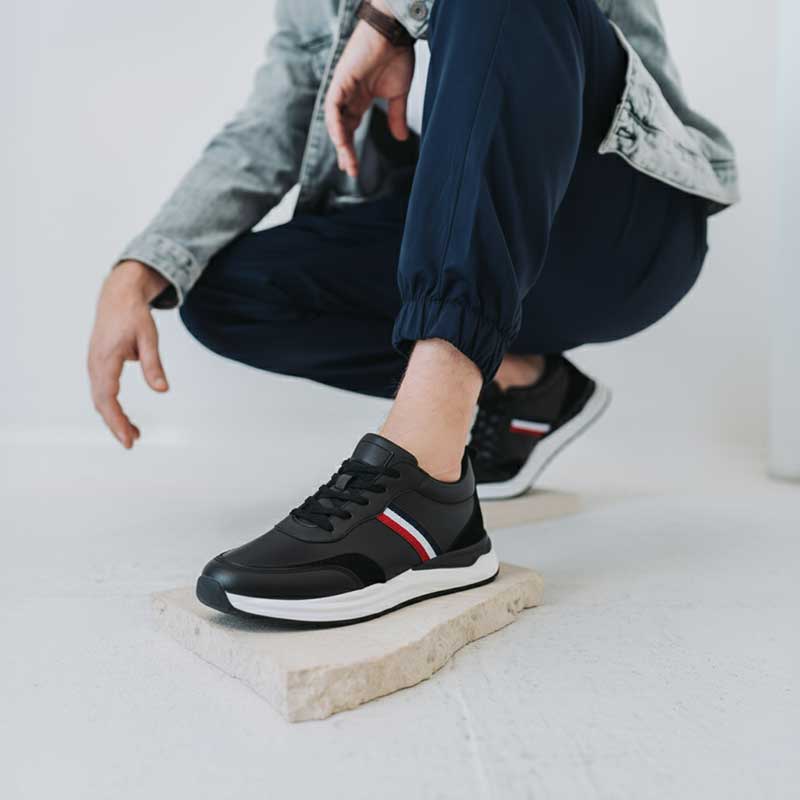 Person wearing black sneakers with a brand logo on a light background