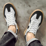 Black and white sneakers with brown soles on a concrete floor