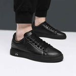 Close-up of sleek black sneakers worn with cropped black pants, showcasing a minimalist design and stylish details.