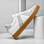 White sneaker with brown sole on a light gray background