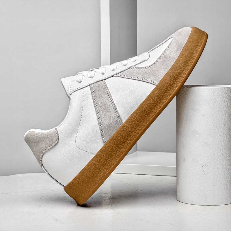 White sneaker with brown sole on a light gray background